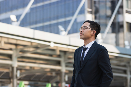 Portrait young Asian executive businessman in suit looking at far away outdoors. Business vision concept.の写真素材