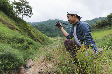 Young Asian traveler man taking photo outdoors scenic nature background. Lifestyle and relaxation...