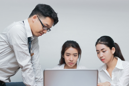 Group of young Asian business people working together on a laptop computer at office. Teamwork...