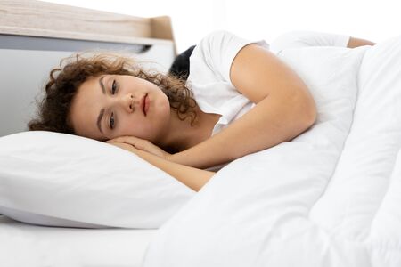 Upset depressed young woman lying on the bed against his husband. Relationship difficulties.