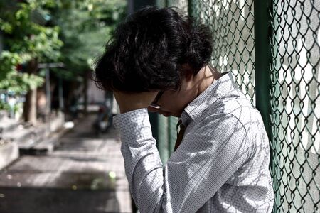Upset stressed young Asian business man sitting on stairs and suffering from severe depression....