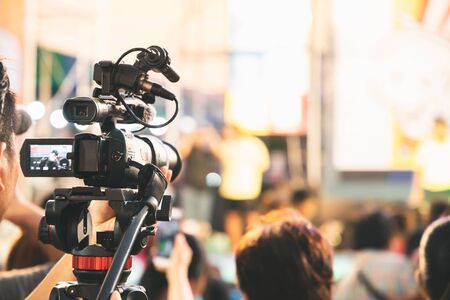 Professional video camera operator working with his equipment at night event.