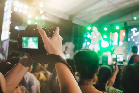 Hands with digital camera taking a picture at stage of music concert