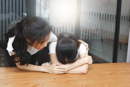 Young Asian woman comforting her depressed friend in living room.の写真素材