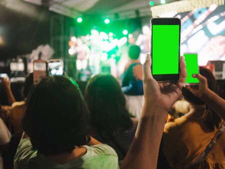Hands of audience crowd people taking photo with mobile smart phone with green screen in party...