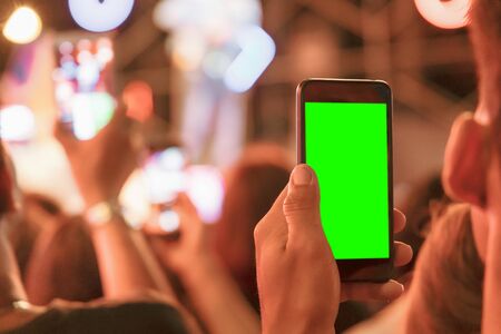 Hands of audience crowd people taking photo with mobile smart phone with green screen in party concert.の写真素材