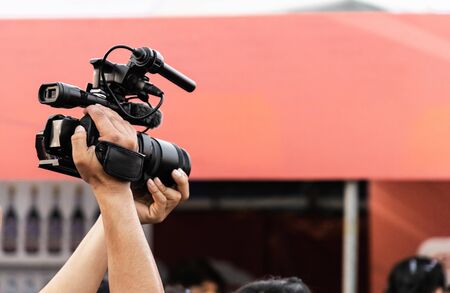 Hands of professional video camera operator working with his equipment at night event.