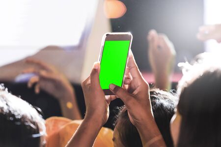 Hands of audience crowd people taking photo with mobile smart phone with green screen in party...