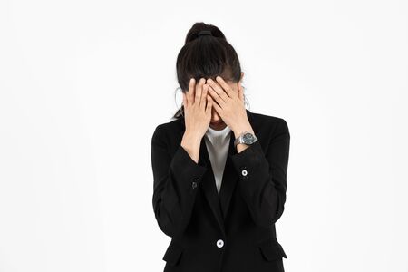 Tired overworked Asian business woman with hands on face suffering from severe depression on white isolated background. Unemployment and layoff concept.
の写真素材