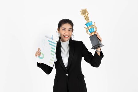 Successful young Asian business woman celebrating with trophy award over white isolated background. Success achievement in business concept.の写真素材