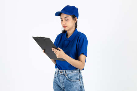 Young delivery Asian woman in blue uniform holding clipboard over white isolated background.の写真素材