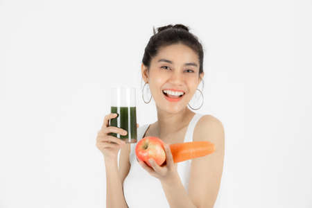 Healthy young Asian woman drinking green detox vegetable smoothie over white isolated background. Vegetarian drink juice, Healthy lifestyle, Fitness and health care concept.の写真素材