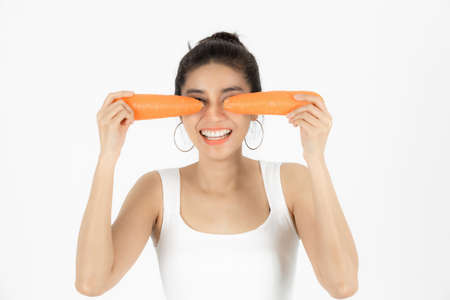 Healthy young Asian woman holding carrot over white isolated background. Vegetarian, Healthy...