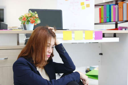 Tired overworked young Asian business woman suffering from severe depression in office.の写真素材
