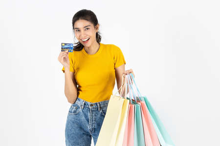 Lifestyle, Consumerism, Sale and Shopping concept. Smiling young Asian woman showing credit card and lot of shopping bag over white isolated background.の写真素材