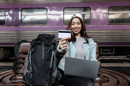 Attractive young Asian backpacker woman with credit card at train station. Ready for travel.の写真素材