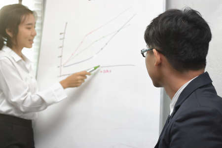 Leadership young Asian business woman looking at camera between listening to presentation in modern office background.の写真素材