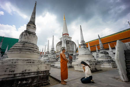 Young Asian woman sit and pray respect monk in the templeの写真素材