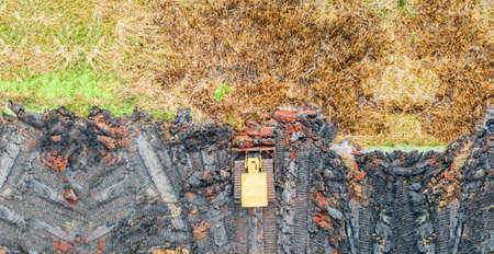 Panoramic aerial view of heavy yellow bulldozer leveling ground at construction site.の写真素材