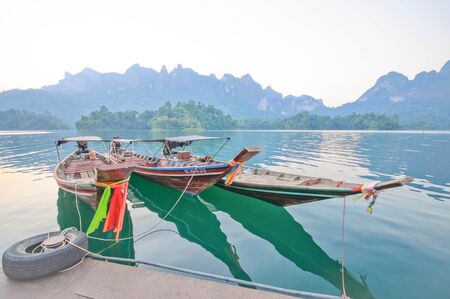 Long-tail boat and lakeside raft houses on Cheow Lan Lake, Khao Sok National Park in southern Thailandの写真素材