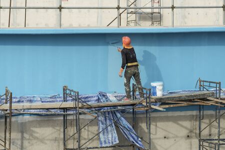 painting facade builder worker "movement" with roller at Water Treatment Plantの写真素材