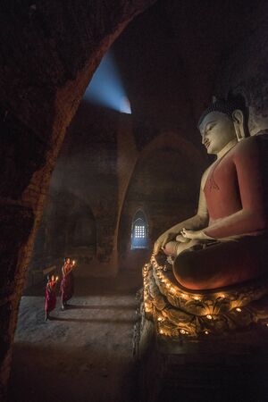 Southeast Asian neophyte praying with candle light in a Buddihist temple in Bagan, Myanmarの写真素材