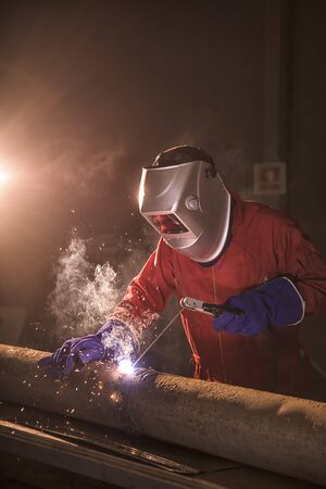 worker weld metal in factory and sparks