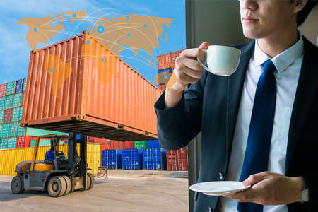 Businessman drinking coffee with logistics container cargo shipyard background. a global commerce and transportation business or logistics conceptのeditorial素材