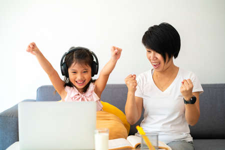 Asian girl and her mother using laptop for online study during homeschooling at home.の写真素材