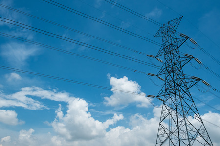 Power tower against clouds and blue sky.