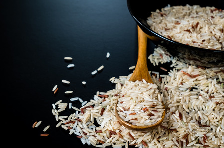 Milled brown rice on wooden spoon and bowl. selective focus.の写真素材