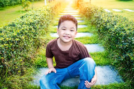 Portrait of young asian boy kid child smiling in garden/public park. Sunlight filter process.の写真素材