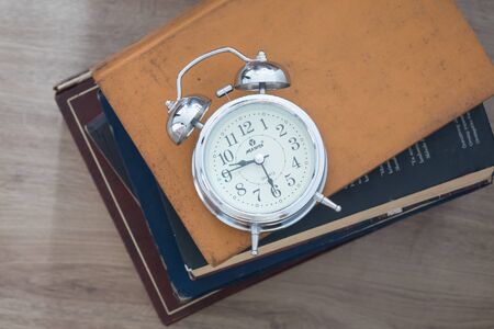 Alarm clock and bookson wooden background.の写真素材