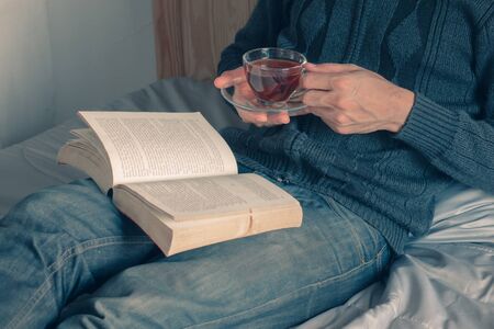 reading the books in bed and enjoying a cup of teaの写真素材