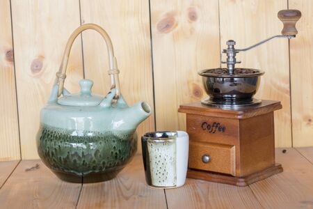 Coffee grinder and a teapot on a wooden background.の写真素材