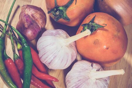 Vegetables (tomatoes, onions, peppers, garlic) on wooden floor