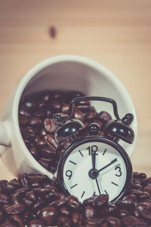 Clock Alarm on Coffee beans. Coffee cup full of coffee beans.の写真素材