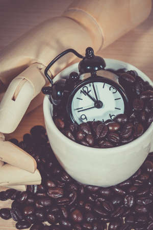 Clock  Alarm on Coffee cup  ,Coffee cup full of coffee beans with on wooden deskの写真素材