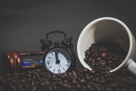 Clock Hourglass Alarm on Coffee beans. Coffee cup full of coffee beans.の写真素材