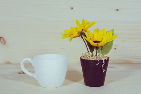 Sunflower in a Flowerpot and a cup of coffee On a wooden backgroundの写真素材