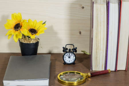 Flower book magnifying glass and clock on the wood floor.