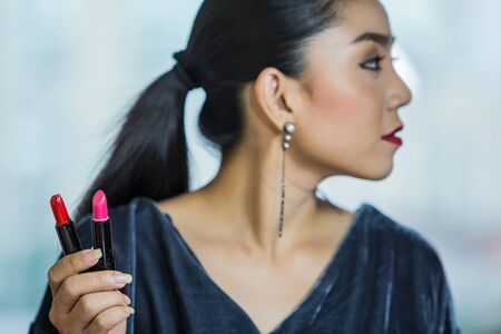 Brunette woman applying make up in hand with mouth lipstickの写真素材