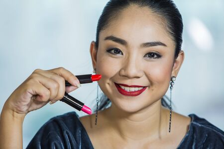 Brunette woman applying make up in hand with mouth lipstickの写真素材