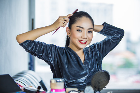 Portrait of beautiful young Asian woman combing her hairの写真素材
