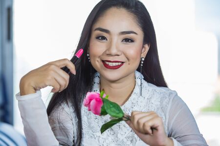 Portrait of beautiful young Asian woman ,Brunette woman applying make up in hand with mouth lipstickの写真素材
