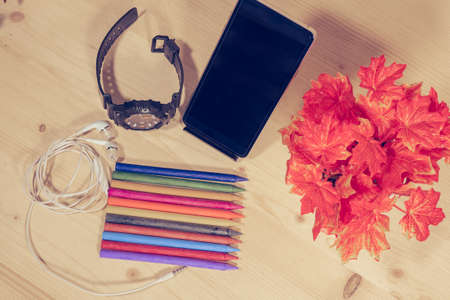Many colorful crayons on wooden background with clock, phone, earphone to create artwork.の写真素材