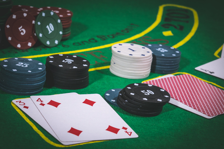 Person playing poker and looking at cards , risk game poker table during a game. Chips, money and cards on the table.の写真素材