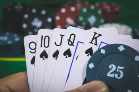 Person playing poker and looking at cards , risk game poker table during a game. Chips, money and...