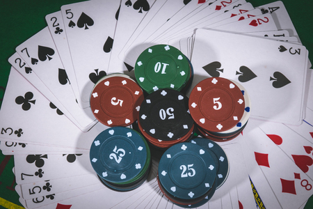 Person playing poker and looking at cards , risk game poker table during a game. Chips, money and cards on the table.の写真素材