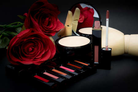 Lipstick,powder and flowers with cosmetics for women To make her look beautiful at work on a black background.の写真素材